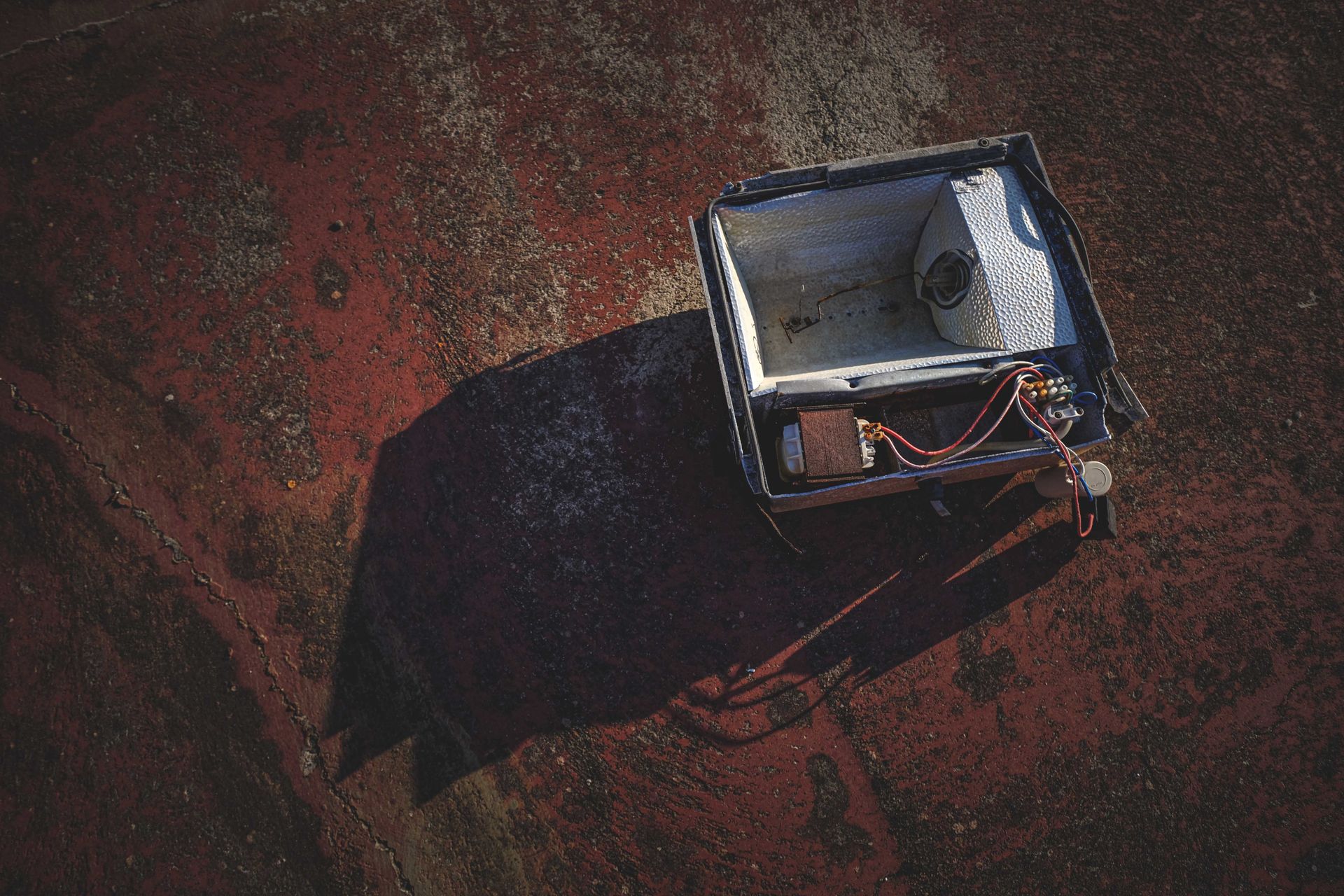 Top view of a damaged floodlight on a weathered, rusty concrete surface.