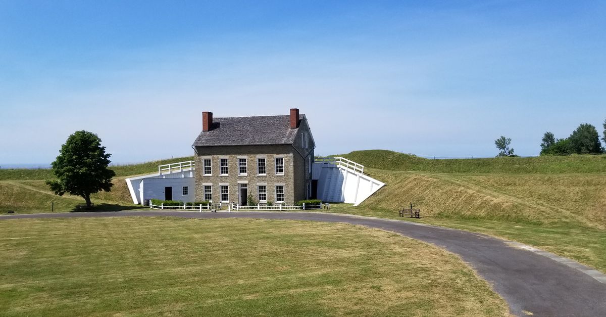 A historic fort building with chimneys set in the green Ontario countryside under a blue sky.