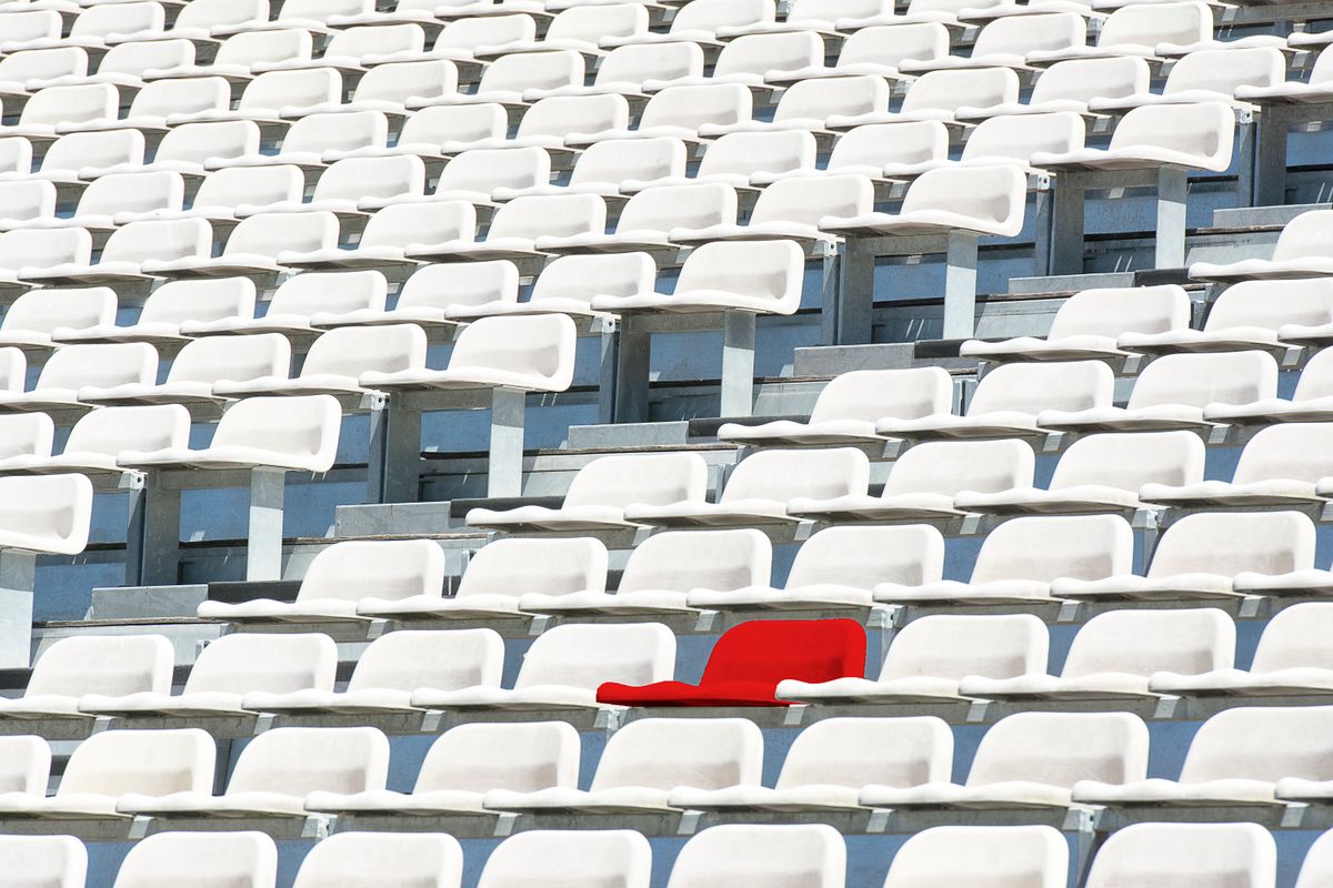 A single red seat standing out among rows of white stadium seats