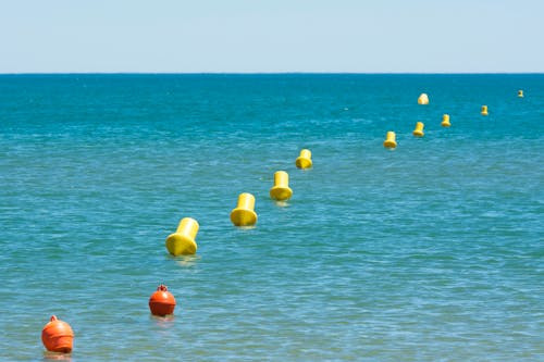 Red and Yellow Buoys Floating on Sea