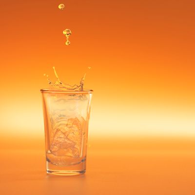 Close-up of an orange liquid splash in a glass with ice — photo by Daniel Sperindeo on Pexels