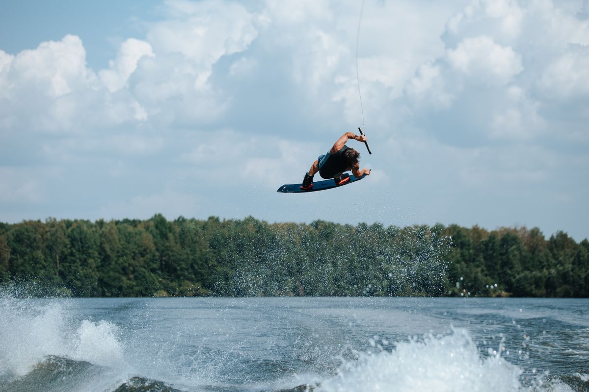 Wakeboarder catching big air above a sunny lake