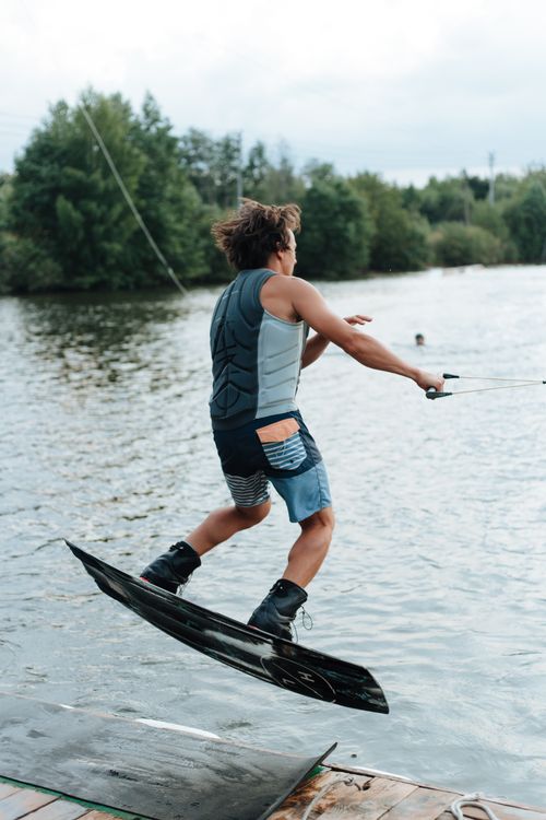 Free Energetic man wakeboarding on a lake, showcasing thrilling outdoor adventure and sports action. Stock Photo