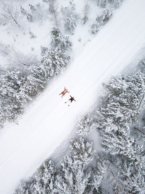 Aerial Photography of Couple Lying Down on Snow Covered Ground