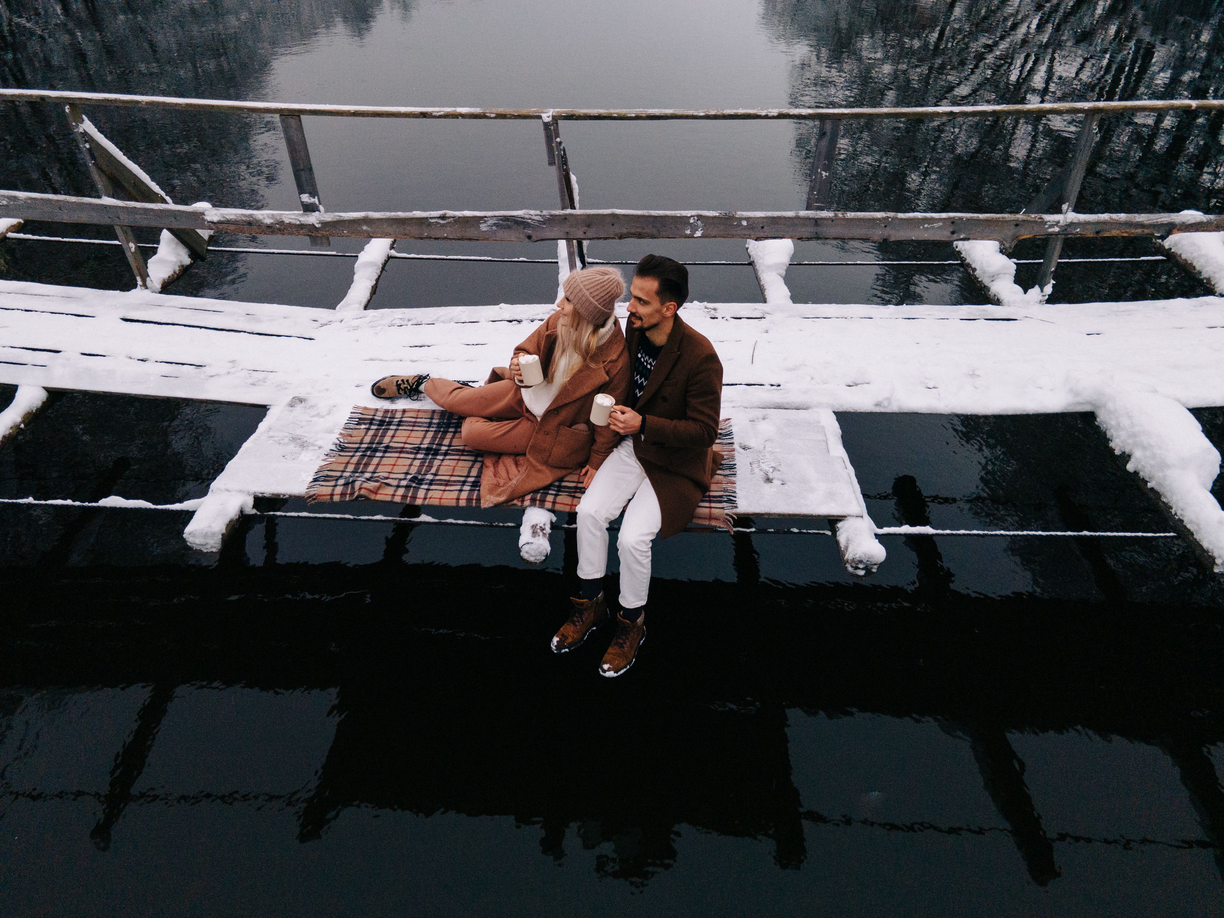 Couple Sitting on Snow Covered Wooden Bridge · Free Stock Photo
