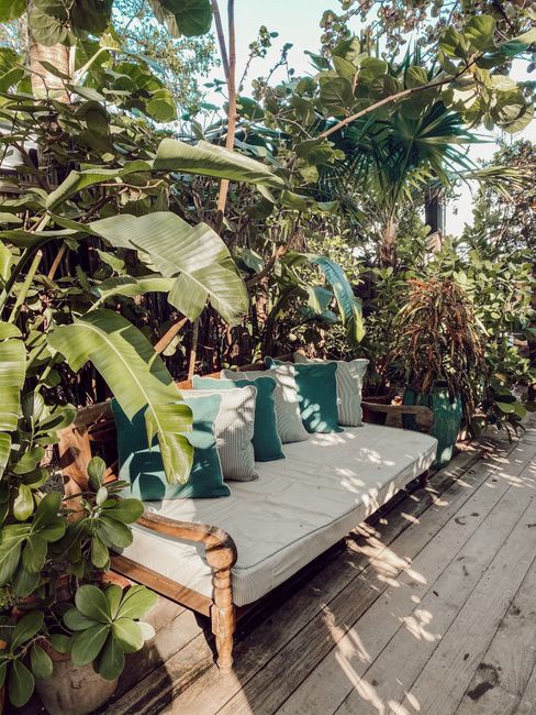 A serene outdoor lounge space featuring a sofa surrounded by lush tropical plants.