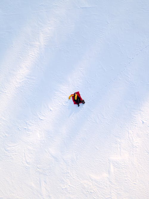 Aerial View of a person Lying Down on a Snow-Covered Field
