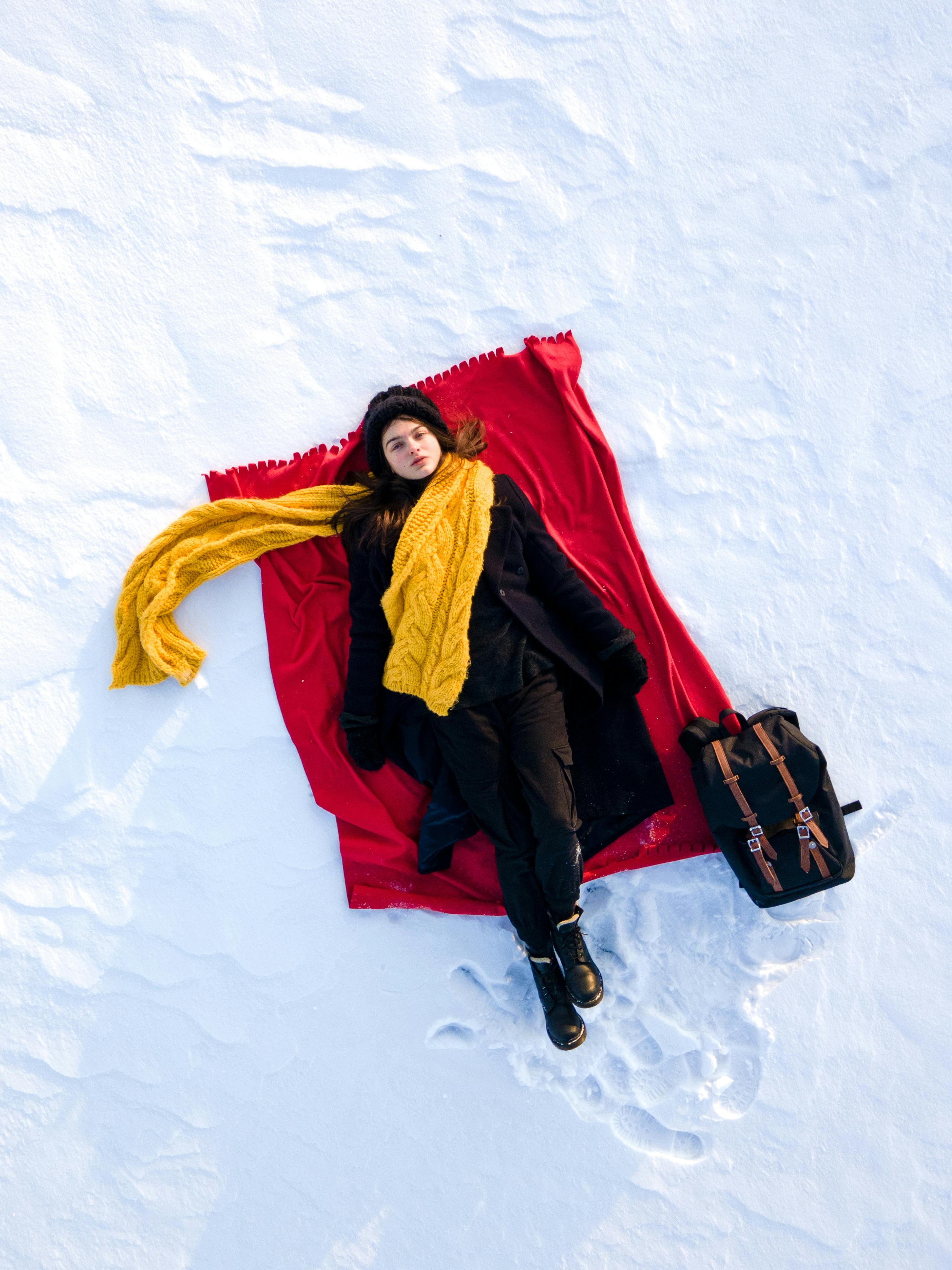 Woman in Black Coat Lying on Snow Covered Ground · Free Stock Photo