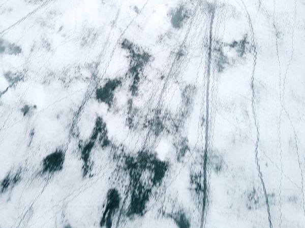 Aerial view of a snow-covered landscape with tracks and patterns — Maksim Goncharenok on Pexels