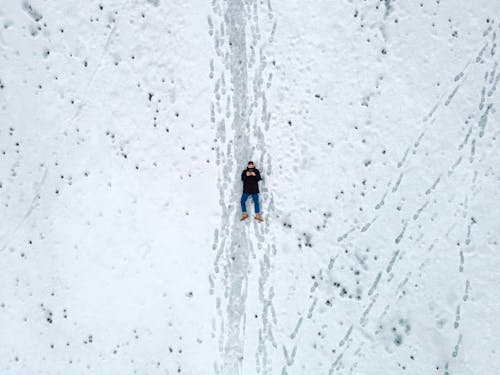 Person Lying Down on Snow Covered Ground