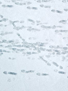 Aerial view of numerous footprints on a smooth snow-covered surface, capturing a wintry scene.