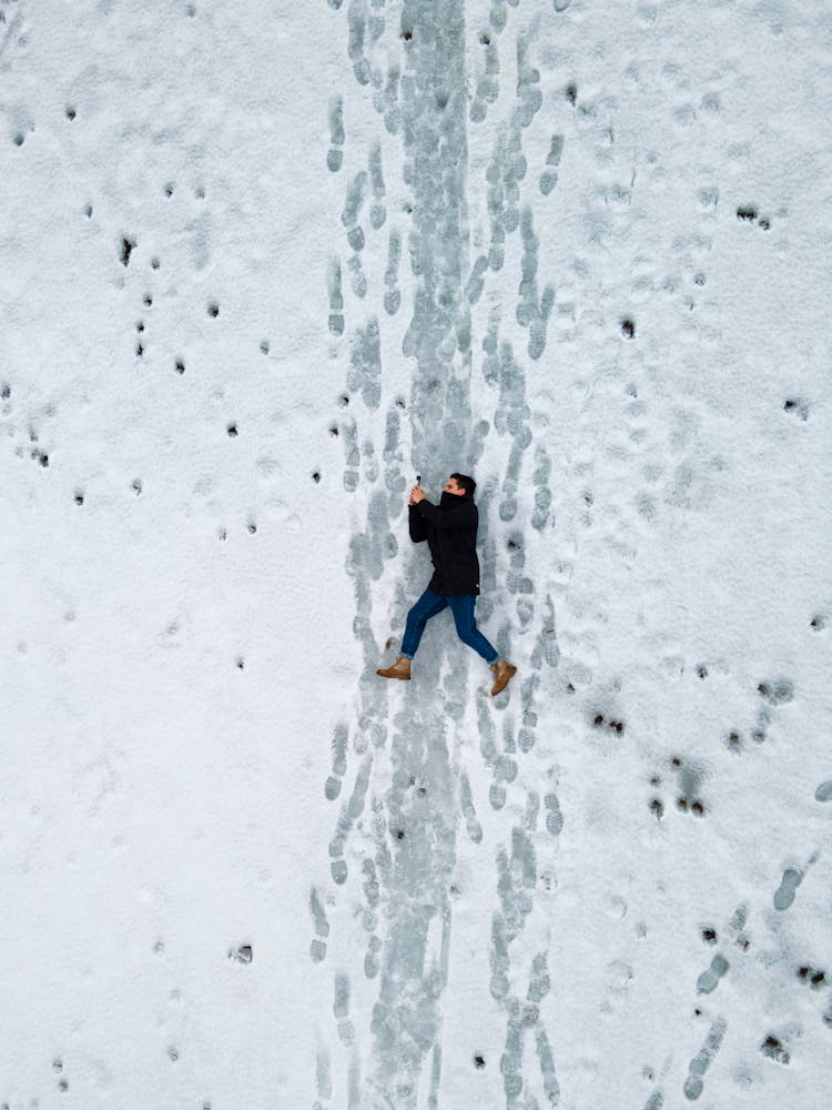 A Person Lying Down On The Snow Covered Ground