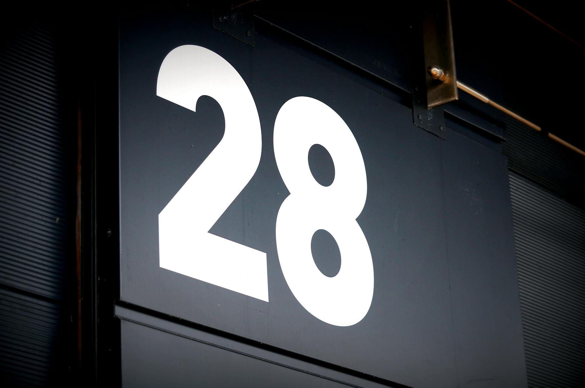 Bold white number 28 displayed on a black panel, ideal for signage or identification.