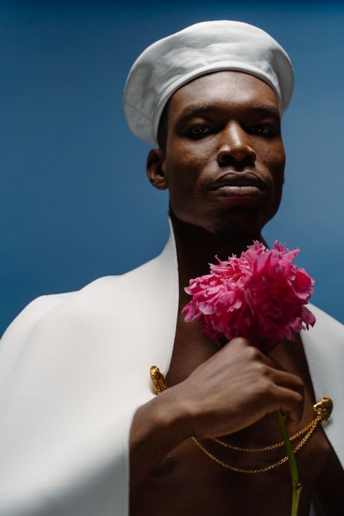 Free Stylish portrait of an adult man holding a pink flower against a blue background. Stock Photo