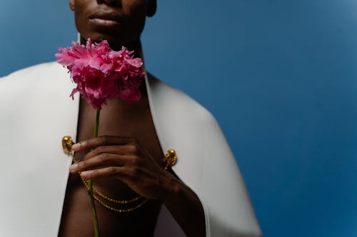 A Man Wearing a Cape Holding a Stem of Flower