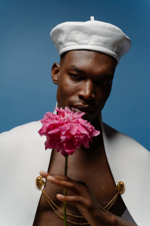 A Man Wearing a White Beret and Holding a Pink Flower