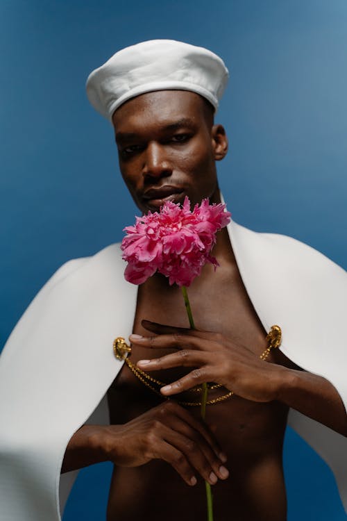 A Male Model Wearing a White Beret and Holding a Pink Flower