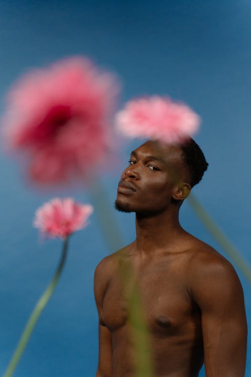 Portrait of a Shirtless Man Posing with Pink Flowers