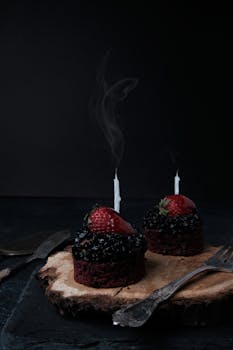 Gourmet chocolate cupcakes topped with strawberries and extinguished candles, perfect for celebrations.