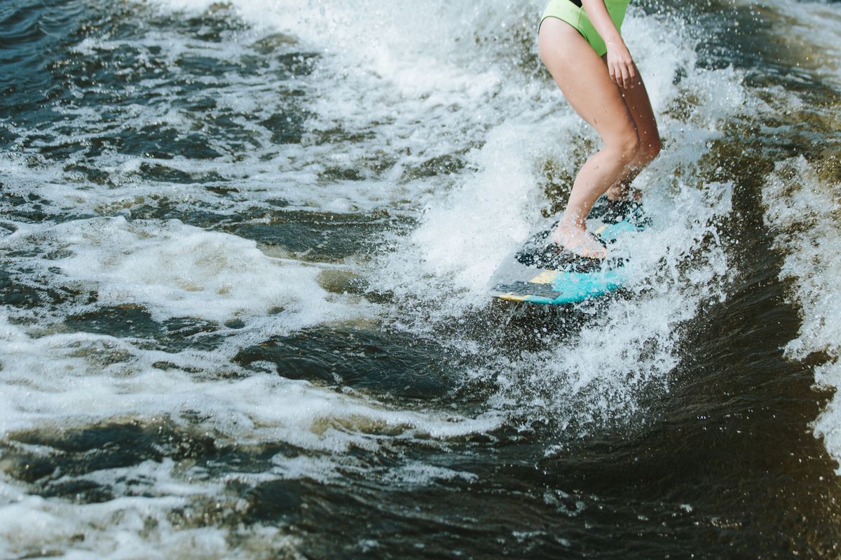 Wakesurfer riding the wave behind a boat on a lake