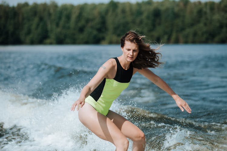 A Woman In Swimwear Doing Surfing On The Sea