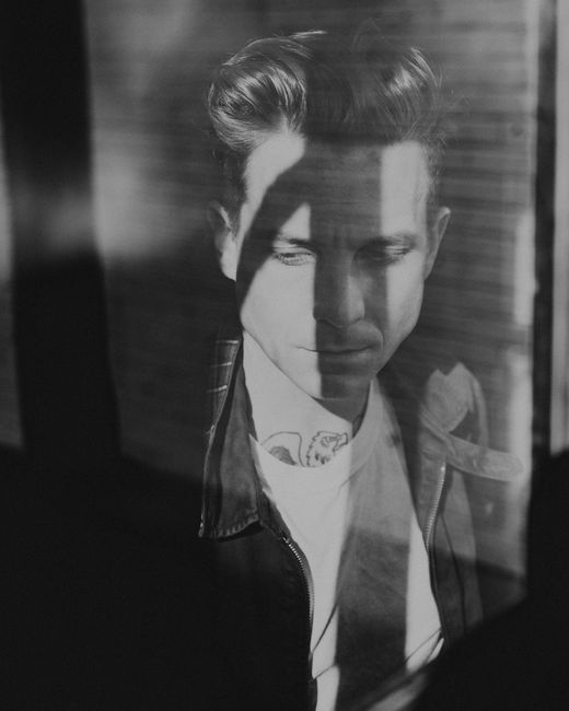 Artistic black and white portrait of a man with shadows creating a dramatic effect.