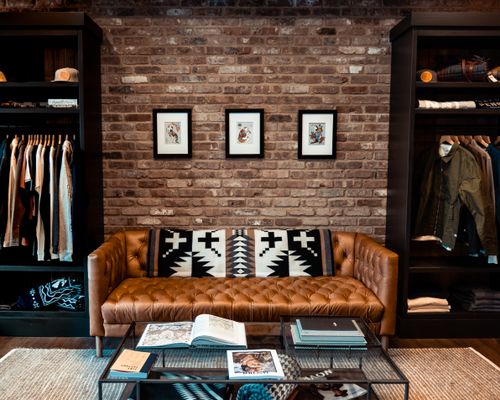 Free Elegant living room with brown leather couch, brick wall, art, and modern decor. Stock Photo