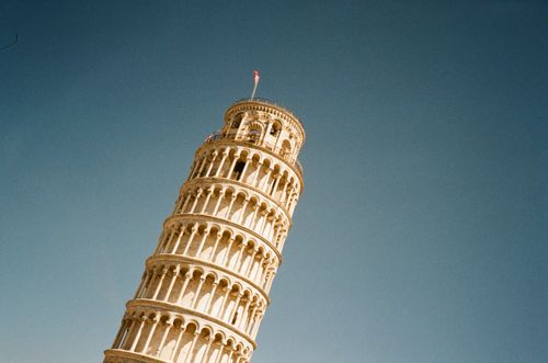 Free Iconic low angle view of the Leaning Tower of Pisa with a clear blue sky overhead, emphasizing its architectural beauty. Stock Photo