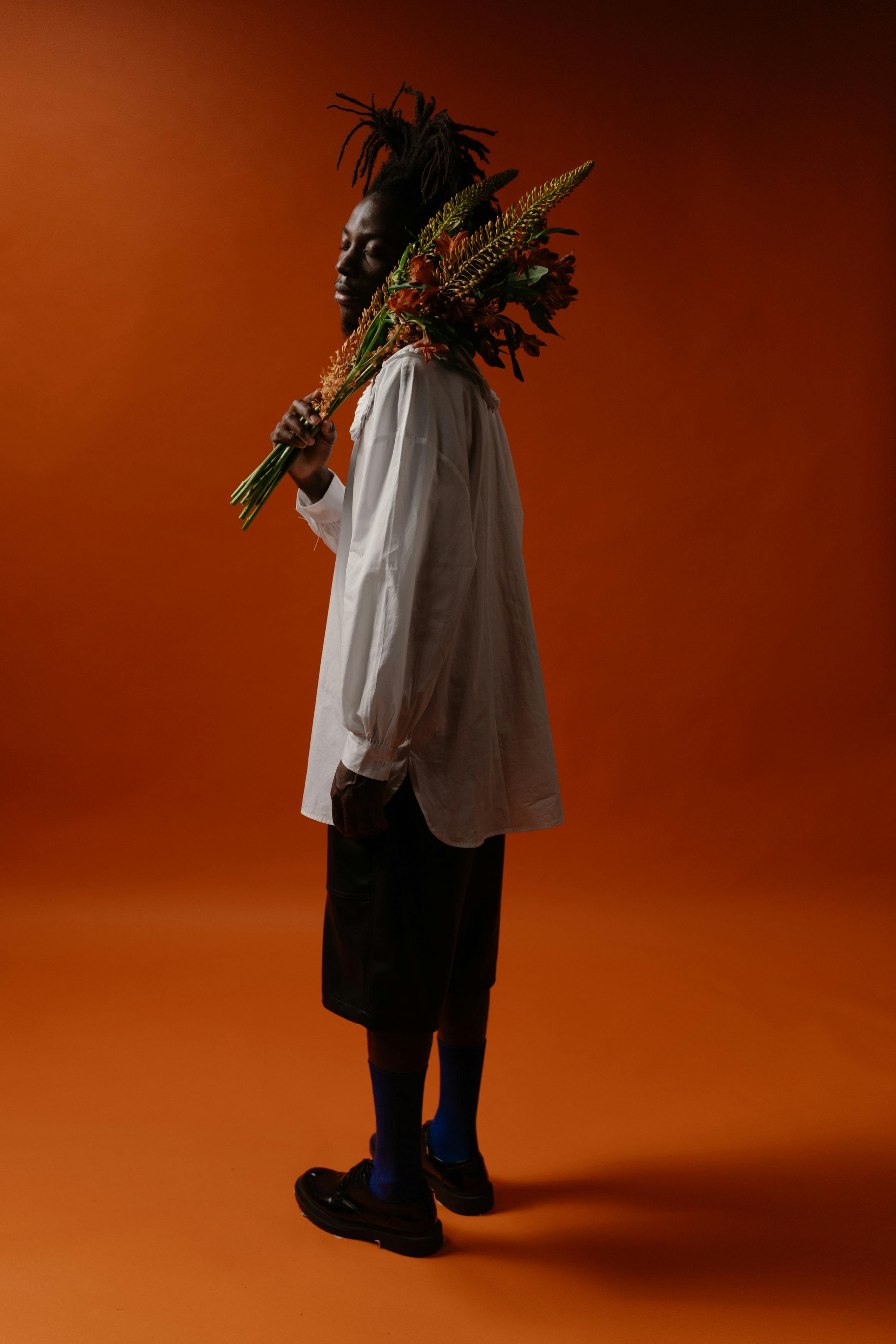 [ColoSach]-artistic-portrait-of-a-stylish-man-holding-a-bouquet-against-an-orange-background.