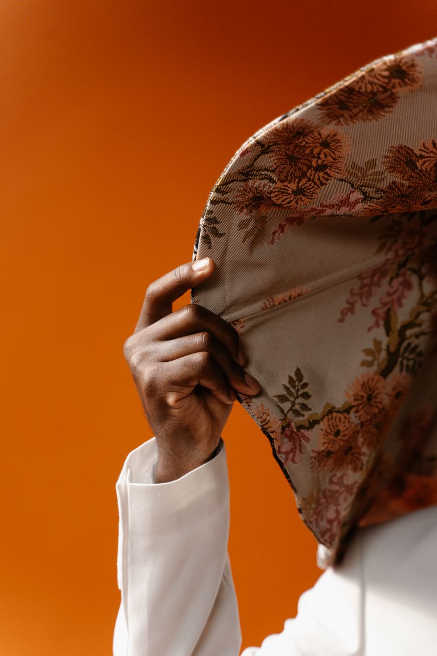 Hand lifting floral print fabric against an orange background