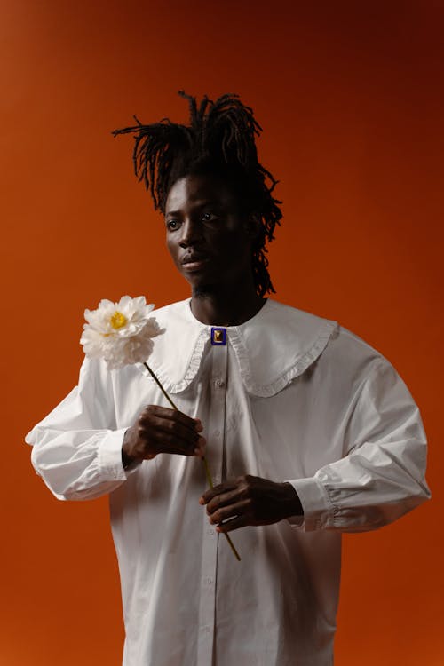 Man Wearing a White Long Sleeve Shirt Holding a Flower