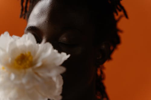 Close-up Photo of a Man Smelling a White Flower