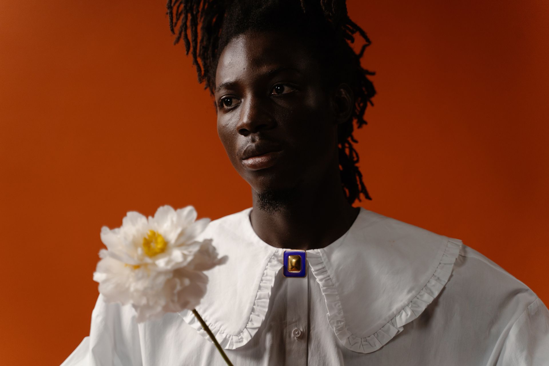 Photo of a Man in a White Top Near a White Peony Flower