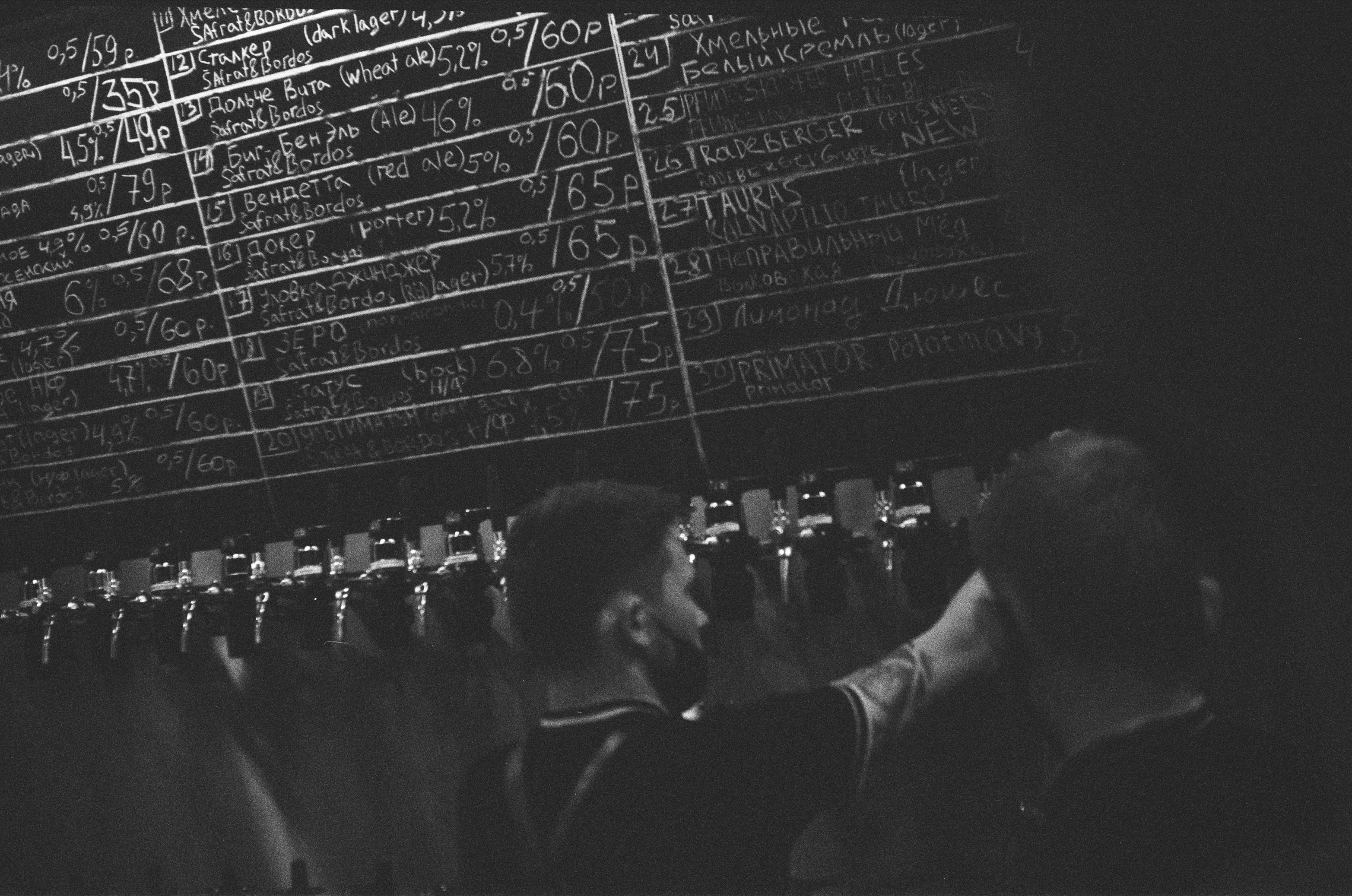 grayscale photo of a chalkboard with handwritten beer brands and prices