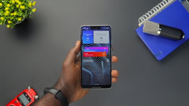 Close-up of a hand holding a smartphone displaying colorful notifications on a black surface.