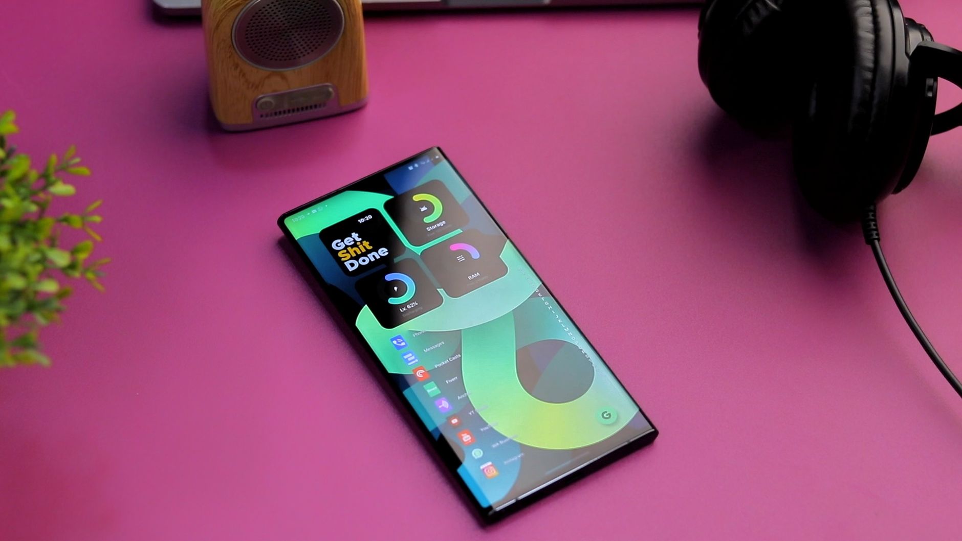 Top-down view of a smartphone, speaker, and headphones on a vibrant pink surface, perfect for tech-themed designs.