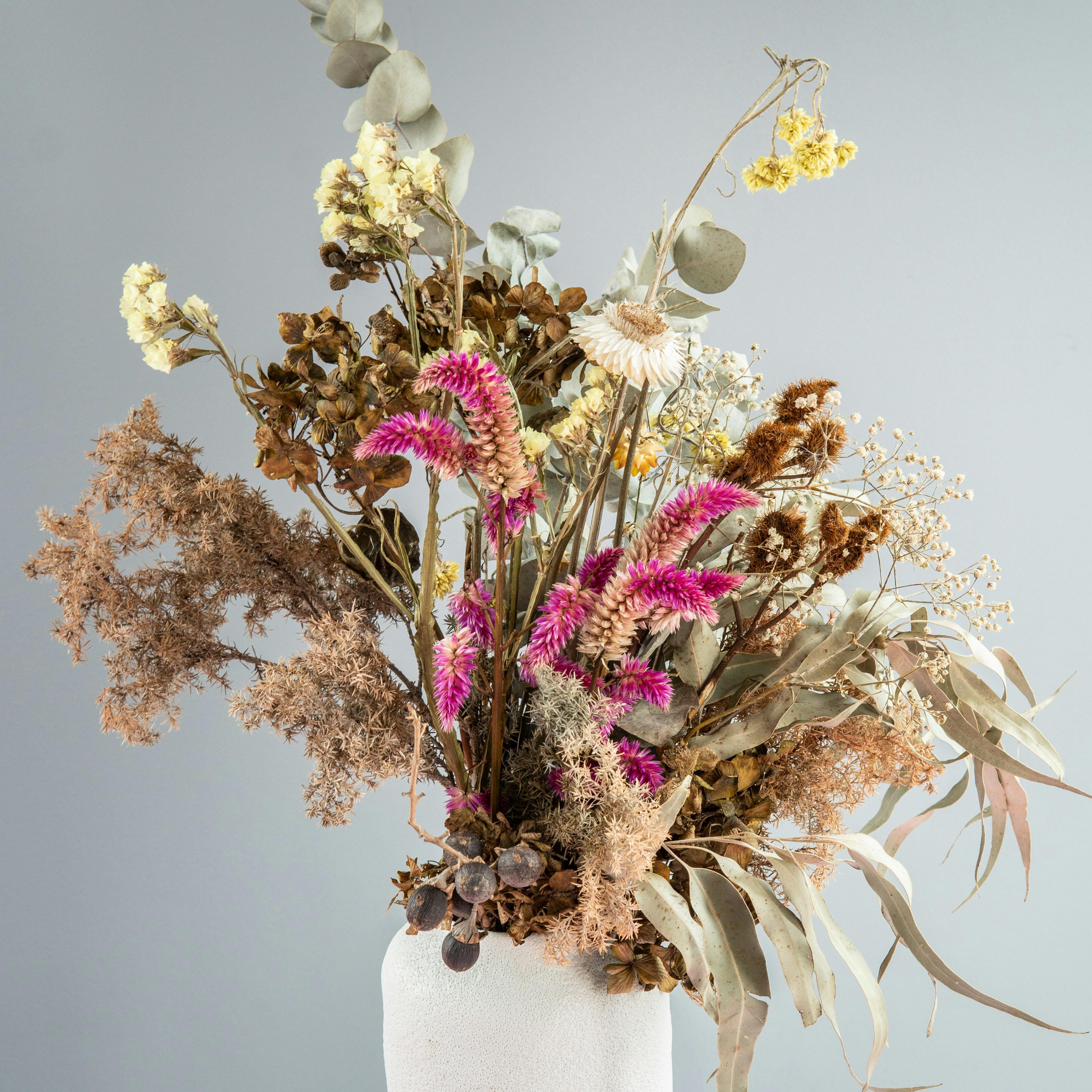 dried flowers in a white ceramic vase