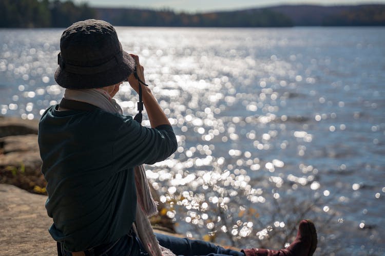 Back Of A Woman In A Hat Photographing The Lake