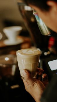 A barista holds a cup of coffee with latte art, creating a warm and inviting atmosphere.