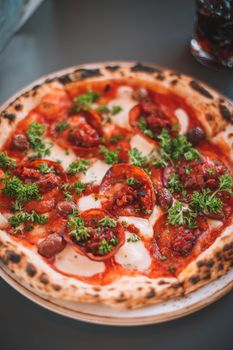 Close-up of a gourmet pepperoni pizza topped with fresh herbs and olives, perfect for food enthusiasts.