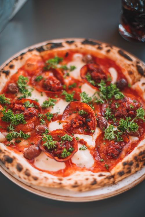 Free Close-up of a gourmet pepperoni pizza topped with fresh herbs and olives, perfect for food enthusiasts. Stock Photo