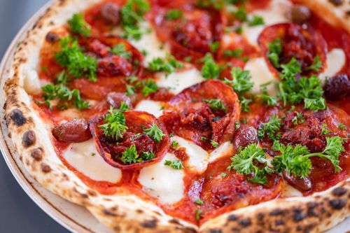 Free Close-up of a pepperoni pizza topped with fresh parsley and olives. Stock Photo