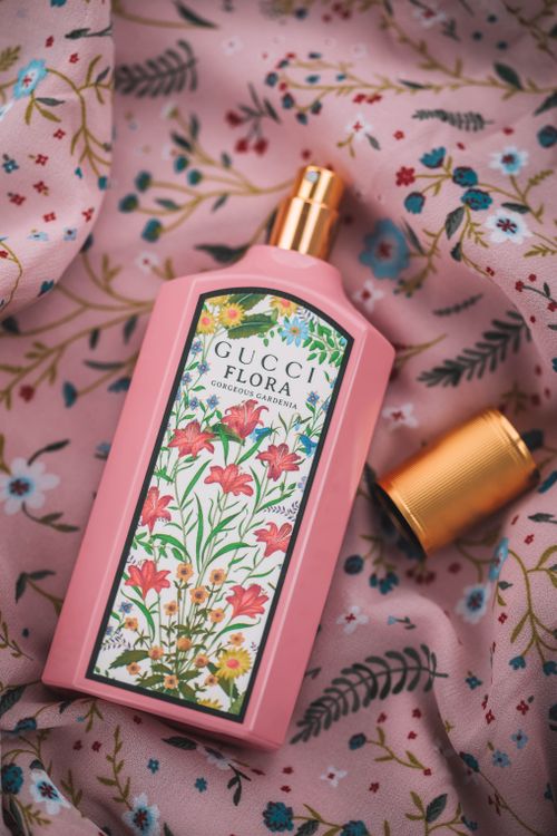 Free Close-up of Gucci Flora perfume bottle on floral fabric, showcasing opulence and elegance. Stock Photo