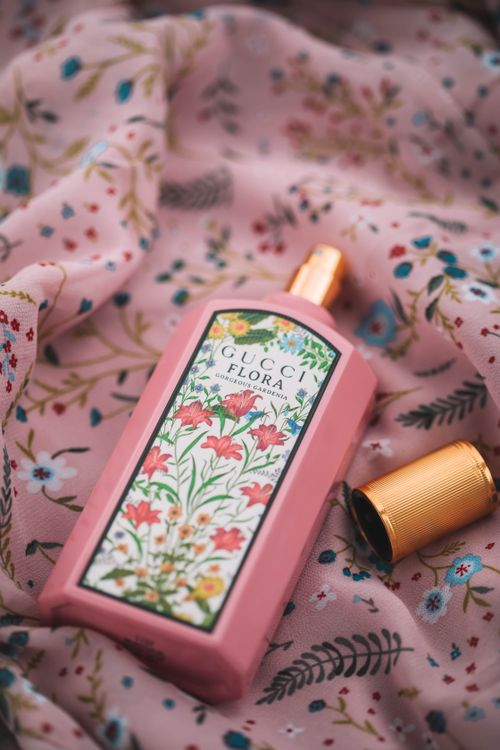 Free Close-up of a floral-themed perfume bottle on pink fabric for a luxurious look. Stock Photo