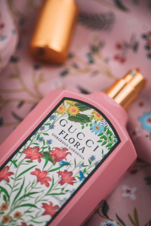 Free Close-up of a floral-themed perfume bottle on a pink decorative fabric, perfect for beauty product photography. Stock Photo