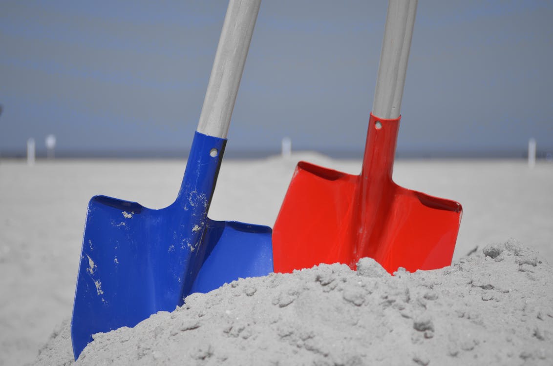 Blue and Red Shovel on Grey Sand during Daytime