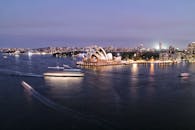 黄昏时分，悉尼歌剧院和港口被壮丽的景色照亮，展现了城市的生活与建筑风貌