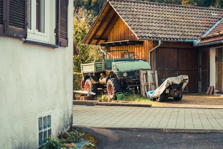 Green Tractor Parked Beside The Barn