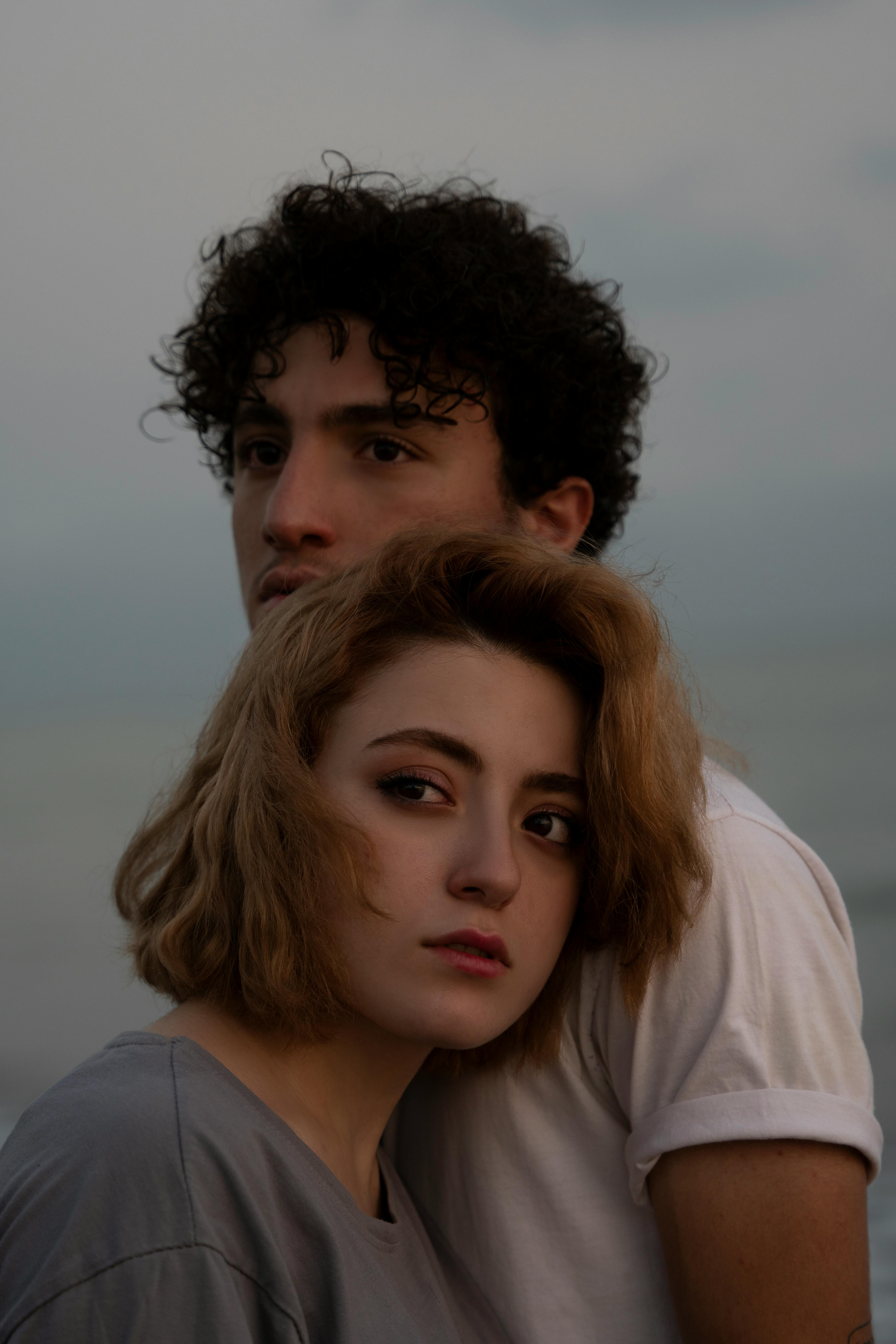 Romantic portrait of a couple standing together by the sea during twilight, conveying deep connection.