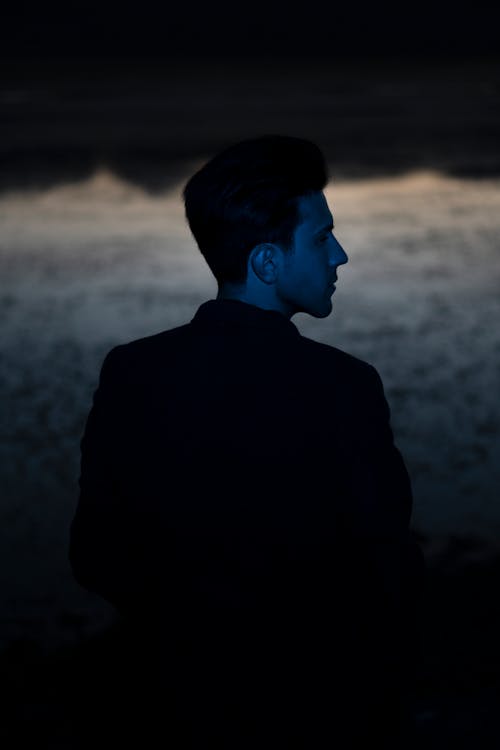 Blue Light on Man Standing by Lake